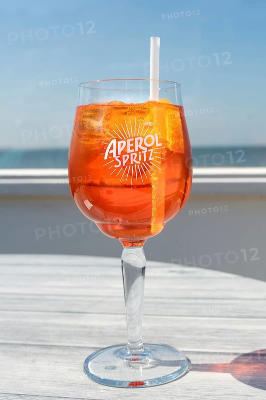 Glass of Aperol Spritz in front of the sea, horizon