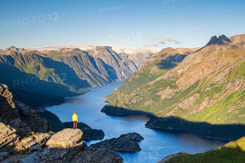 Hiker looking from Seiskallåfjellet into the Nordfjorden, Svartisen Glacier in the background, Saltfjellet Svartisen National Park, Helgeland Coast, Rødøy, Nordland, Norway, Europe