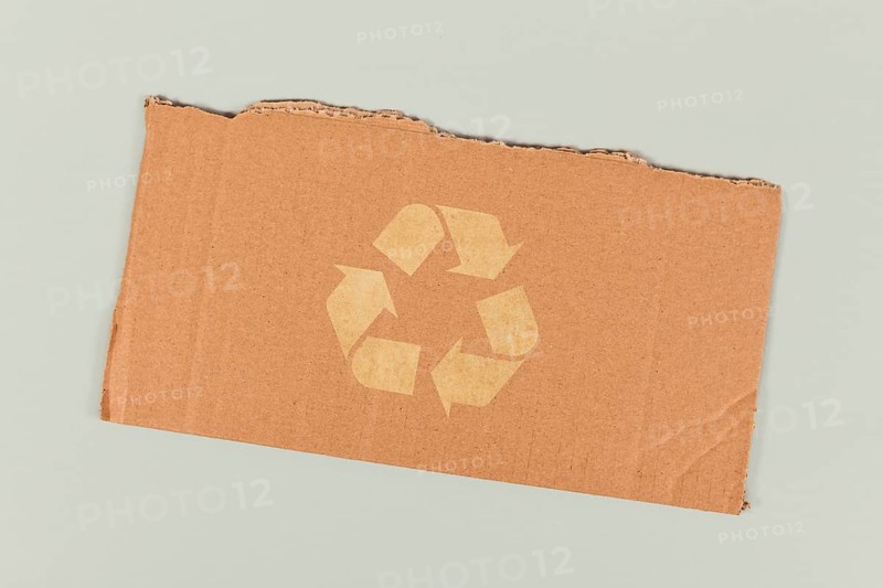 Red recycling arrow symbol on piece of cardboard