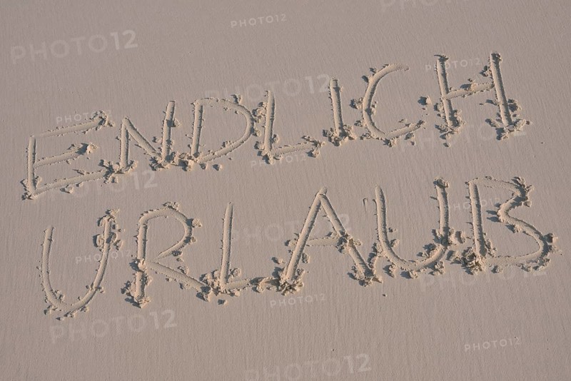 Writing in the sand "endlich Urlaub", German for "finally holidays"