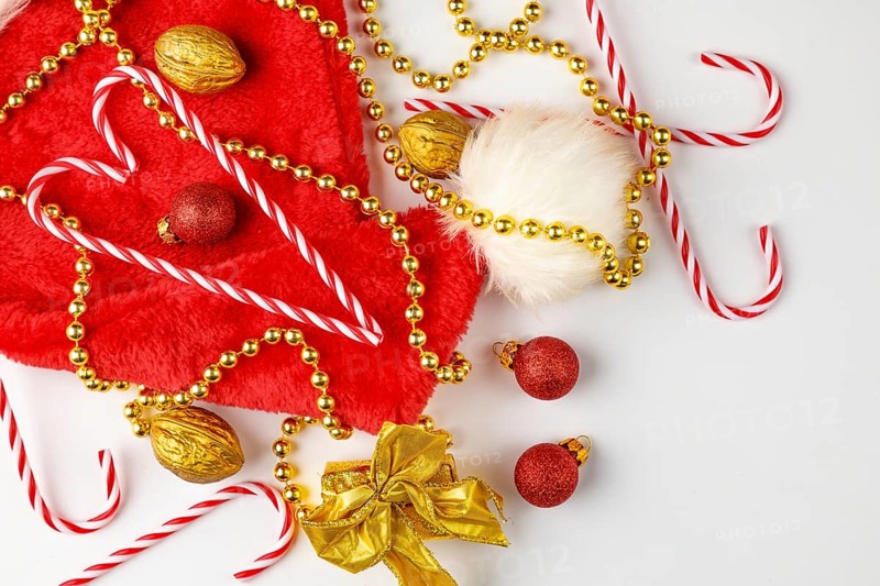 Christmas hat with candy canes, golden pearl necklace and nuts on a white background