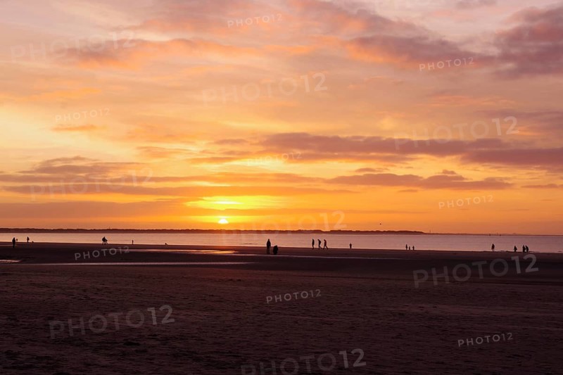 Landscape, Sunset, Beach, Colour, Langeoog, Lower Saxony, Germany, The sky has turned orange. Individual walkers walk by the sea in the light of the setting sun, Europe