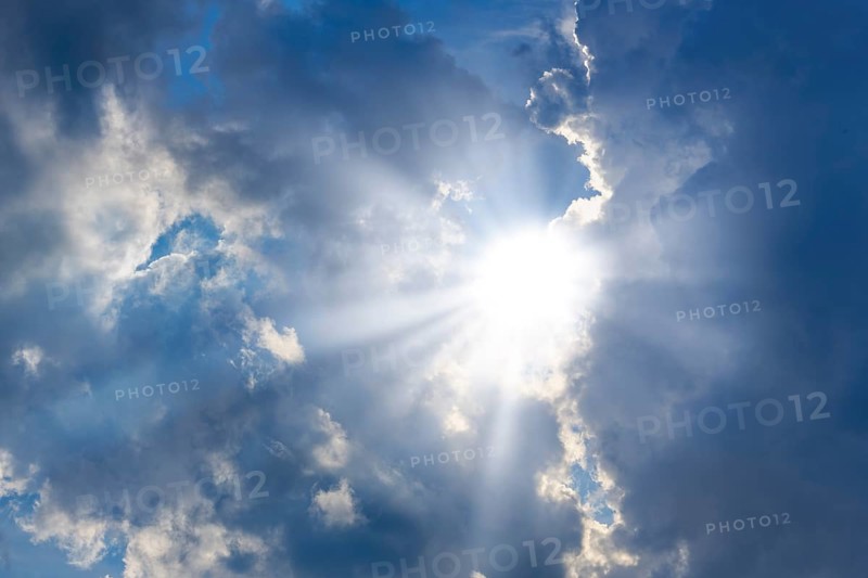 Rain clouds with sun shining through, rays of sunshine, blue sky
