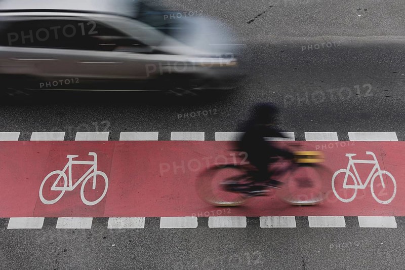 A cyclist rides on a marked cycle path on Schlossstraße and is overtaken by a car in Berlin, 27/02/2024