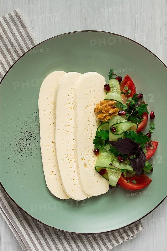 Sliced Imeruli cheese, Georgian cheese, with vegetables, top view, no people