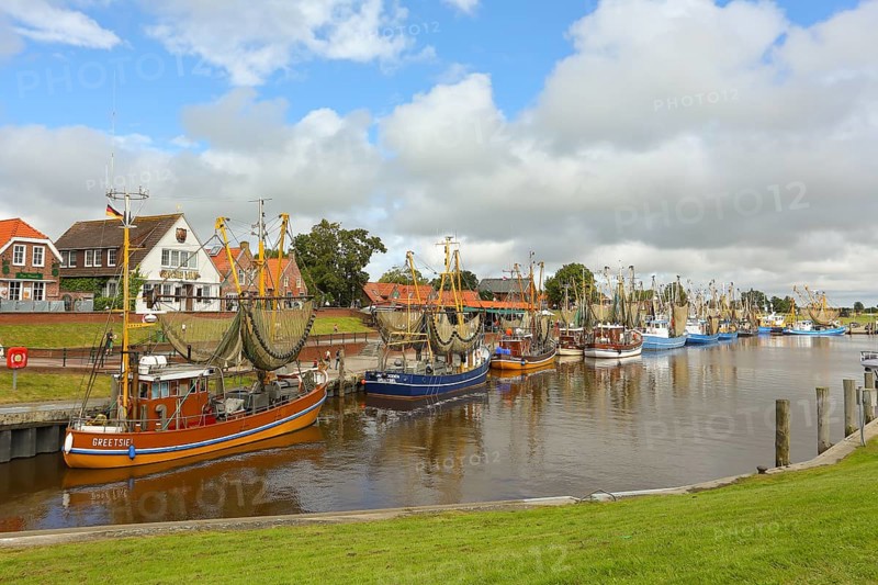 View of historic houses with colourful facades at the old harbour of Greetsiel, with fishing boat, under blue sky, Greetsiel, East Frisia, Lower Saxony, Germany, Europe