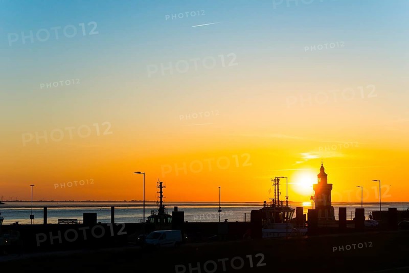 Pingelturm, historic lighthouse in the harbour, atmospheric, golden, beautiful sunset, silhouette in front of the calm sea and the warm light of the sky, bright orange, boats, cutters, in the background the islands Langlütjen I and II, twilight, evening, dusk, maritime, calm atmosphere, mouth of the Weser into the North Sea, Outer Weser, coast, Bremerhaven, Land Bremen, Germany, Europe