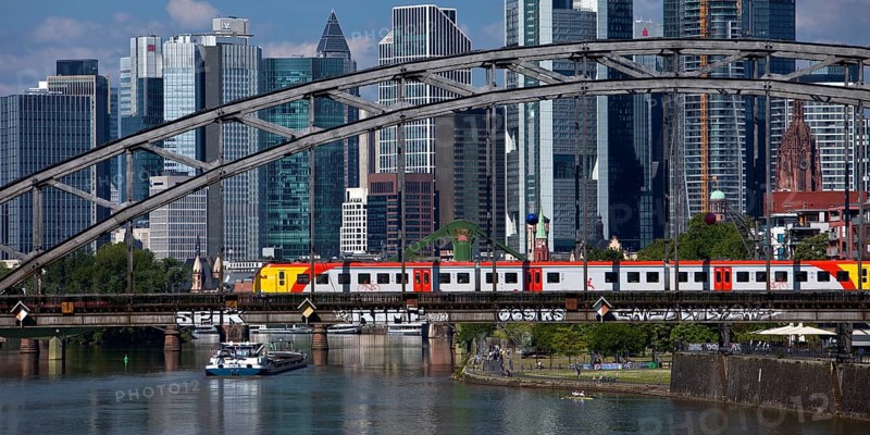 Main with regional railway on the Deutschherrnbrücke and a cargo ship in front of the skyline of Frankfurt am Main, Hesse, Germany, Europe