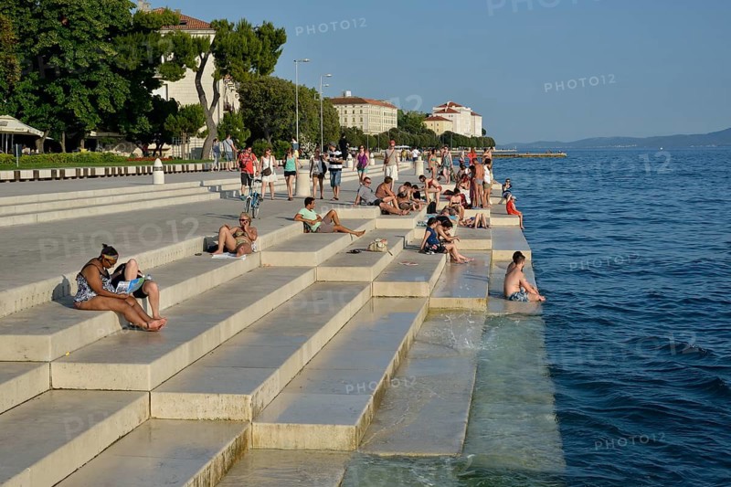 Visitors basking in the evening sun at the Sea Organ by architect Nikola Bašic, Zadar, Dalmatia, Croatia, Europe