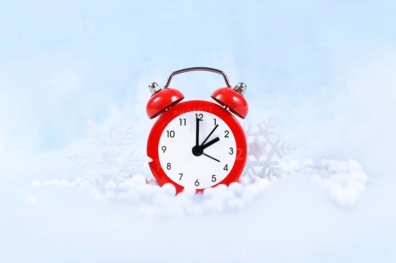 Winter time change for daylight saving in Europe on October 31st concept with red alarm clock between snow