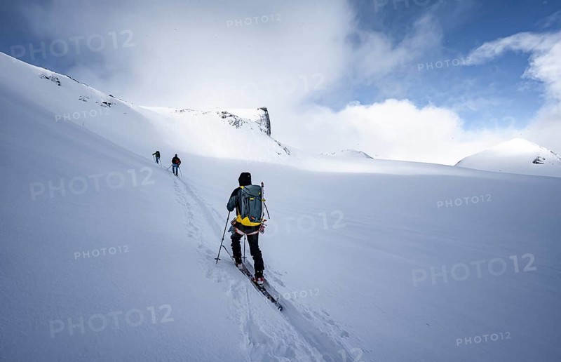 Three ski tourers in a snowy mountain landscape, ascent to the Wildhorn, cloudy mood, high tour, Bernese Alps, Bernese Oberland, Switzerland, Europe