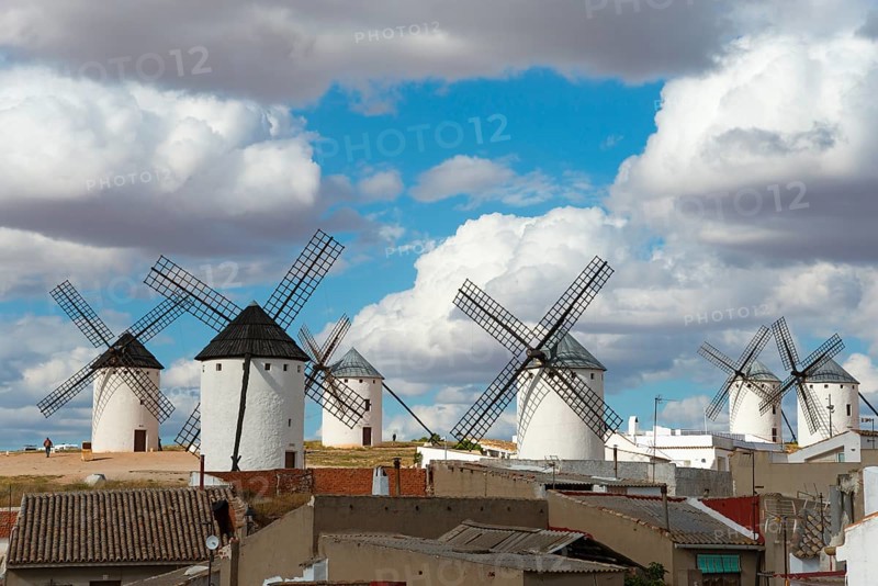 Several mills in a rural area, with old buildings in the foreground and a cloudy sky above, Campo de Criptana, Ciudad Real province, Castilla-La Mancha, Route of Don Quixote, Spain, Europe