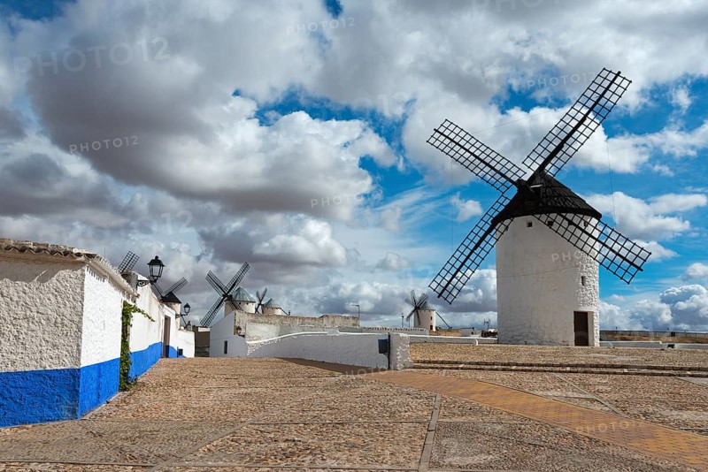 White windmills with blue stripes on old cobbled streets under a cloudy sky, Molino Sardinero, Campo de Criptana, Ciudad Real province, Castilla-La Mancha, Don Quixote Route, Spain, Europe