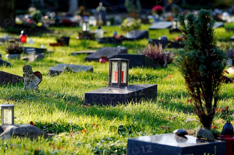 Lantern on a gravestone in a cemetery with graves of the poor against a blurred background
