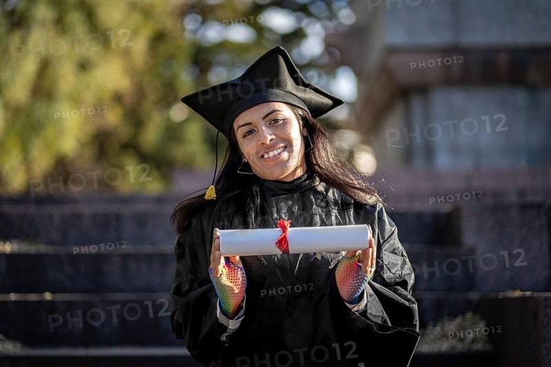 Transgender woman recent graduated, dressed in cap and gown, showing off his degree celebrating