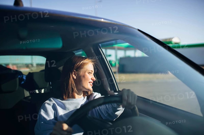 Young beautiful woman driver driving a car, happy trip, spring travel