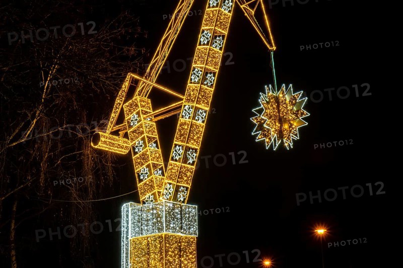Construction crane symbol of Shipyard Holiday illuminated decorations in Gdansk Poland. Beautiful Christmas fair at night. Advent winter time in Europe background. Christmas Markets in December Ornamented for celebration