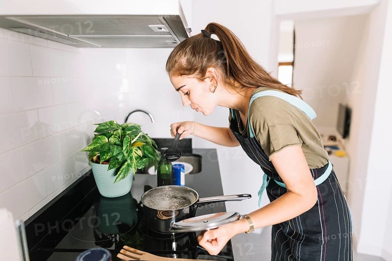 Young woman tasting soup kitchen