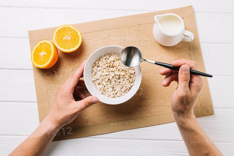 Person having oatmeal halved orange milk jute placemat white surface. High resolution photo