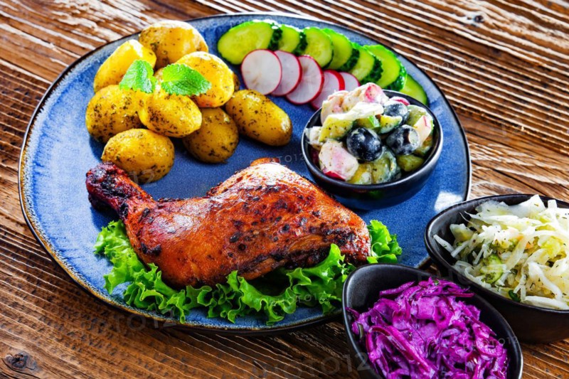Baked chicken leg with potatoes and vegetable salads