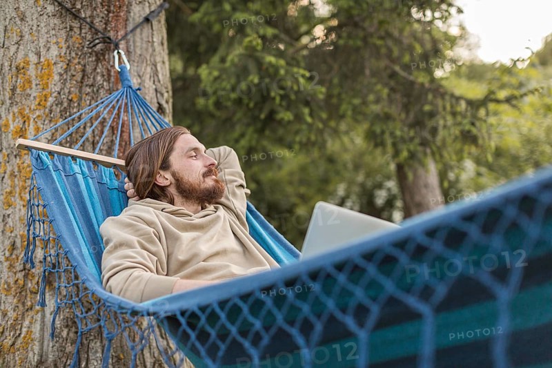 Man hammock enjoying nature with laptop
