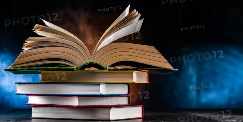 A composition with an open book lying on a stack of other books
