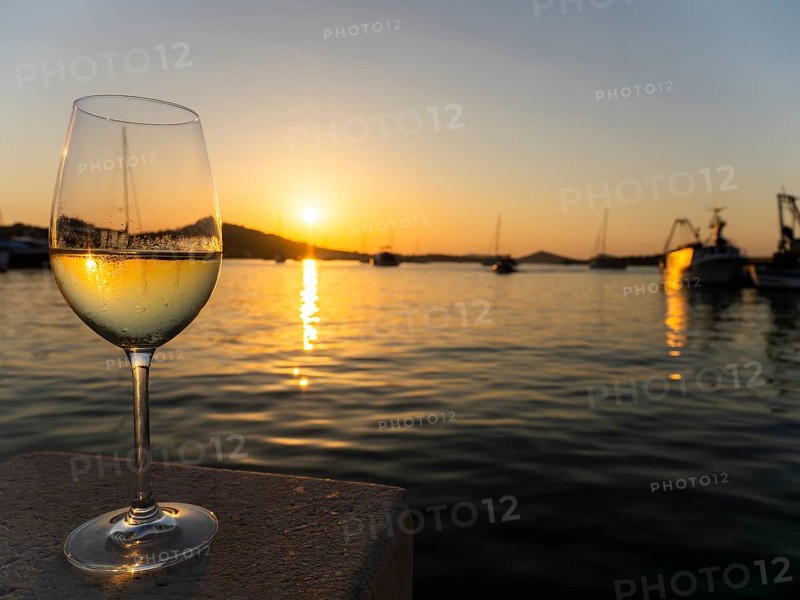 Sunset shimmering through a glass of white wine, evening mood in the harbour, boats and sailing ships, Murter harbour, Murter, Croatia, Europe