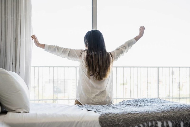 Rear view woman sitting bed stretching her arms. Resolution and high quality beautiful photo