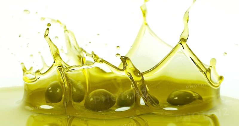 Olives Falling into Olive Oil against White Background