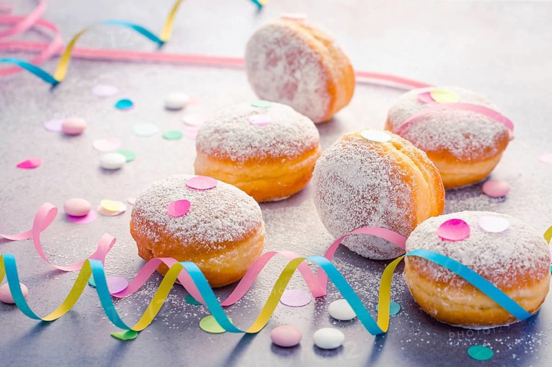 Traditional Berliner for carnival and party. German Krapfen or donuts with streamers and confetti. Colorful carnival or birthday image