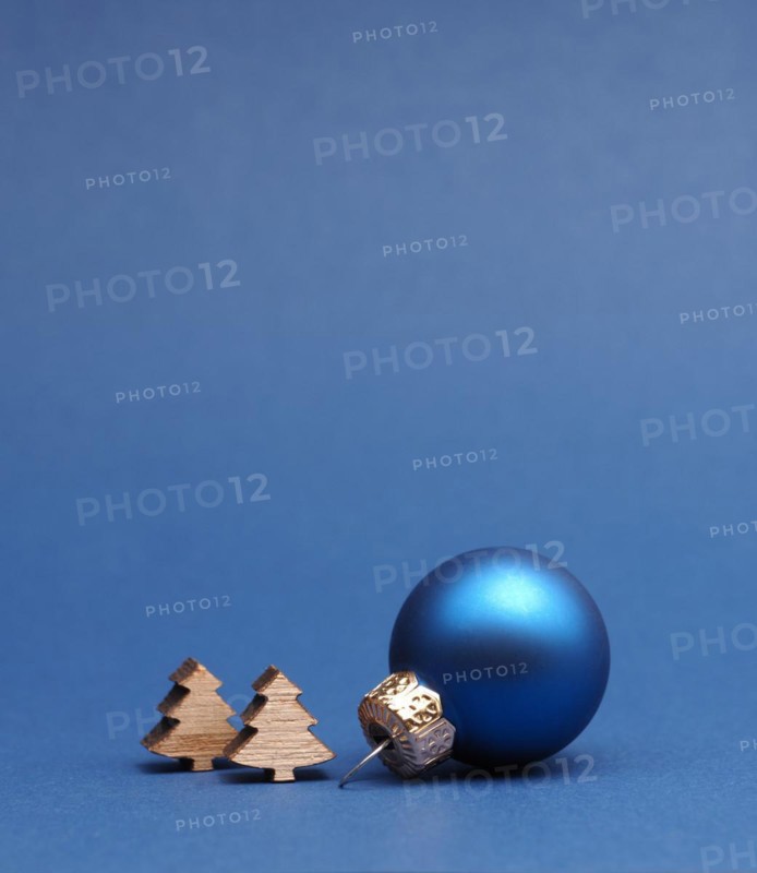 Blue Christmas tree ball with small wooden tree shapes on a blue paper background with space for your text