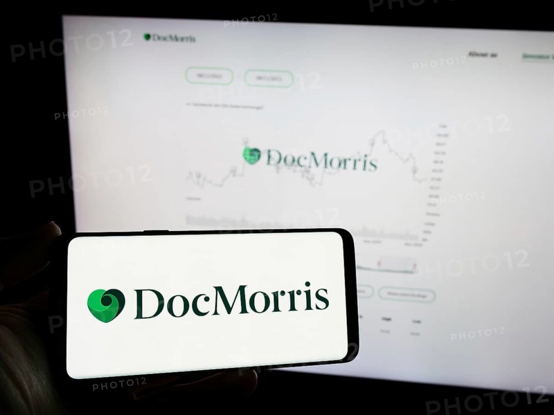 Stuttgart, Germany, 11-08-2023: Person holding mobile phone with logo of Swiss online pharmacy company DocMorris AG in front of business web page. Focus on phone display, Europe