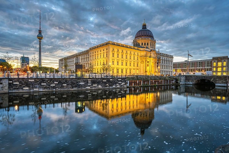 The rebuilt Berlin City Palace with the television tower and some dark storm clouds at dawn