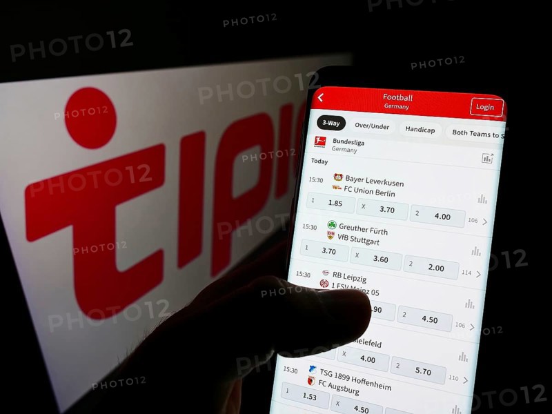 Stuttgart, Germany, 01-08-2022: Person holding smartphone with website of sports betting company Tipico Co. Ltd on screen in front of logo. Focus on center of phone display, Europe