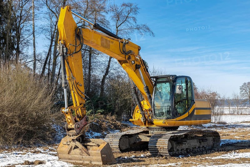 Large excavator parked in a meadow in winter