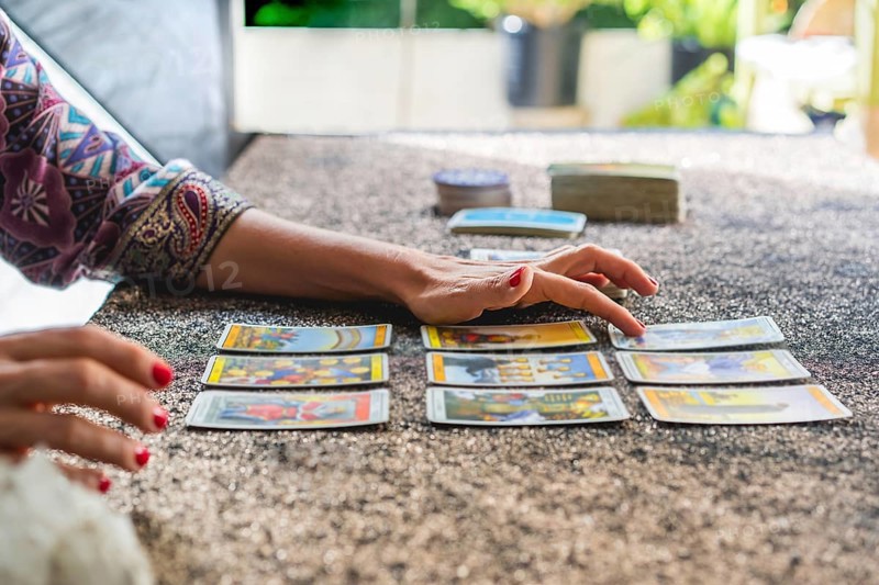 Side view of a tarot reader's hands reading the cards