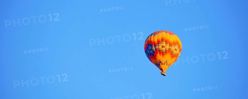 Flying hot air balloon against bright blue sky