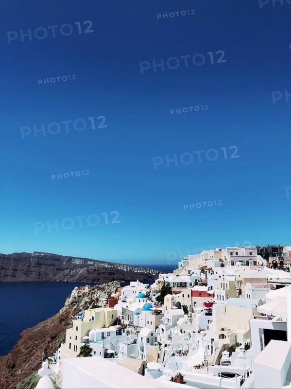 Amazing panorama view of beautiful Oia town on Santorini volcanic island, Greece, Aegean Sea. Traditional and famous houses and churches with blue domes, roofs and bright white walls, Europe