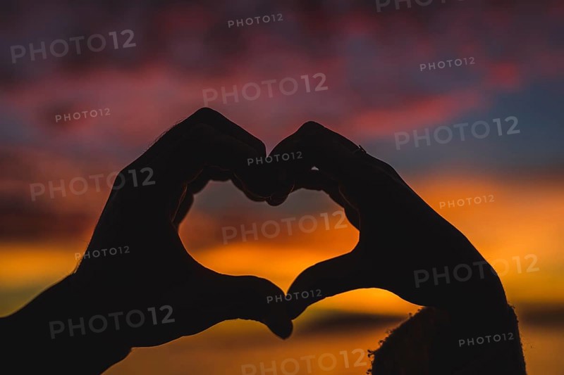 Couple making heart shape from hands sea shore