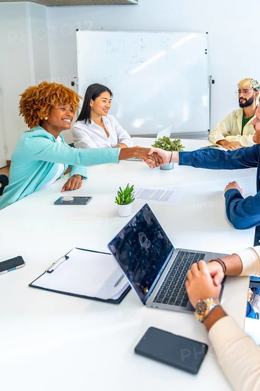 Vertical photo of multi-ethnic people greeting shaking hands on a meeting in a coworking