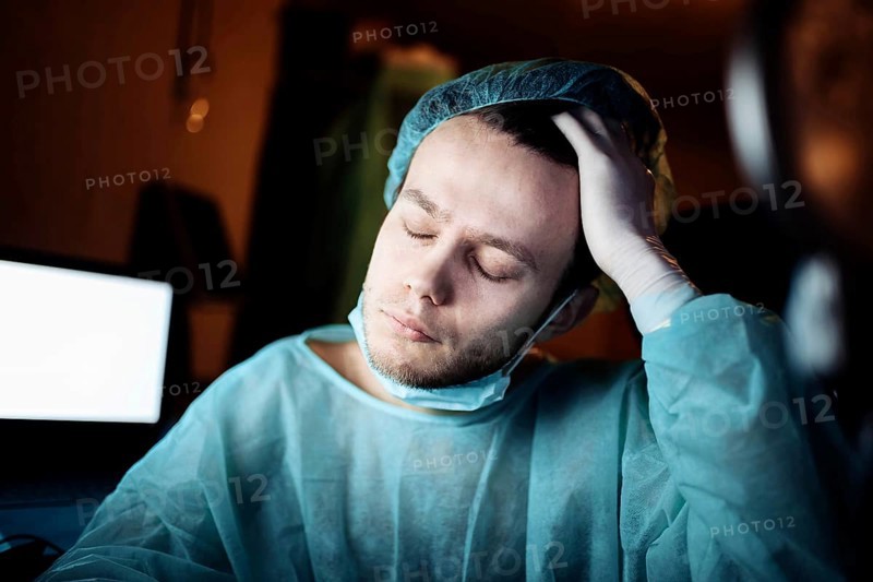 Tired sad surgeon doctor in depression upset and holds his head. Medical error and professional burnout
