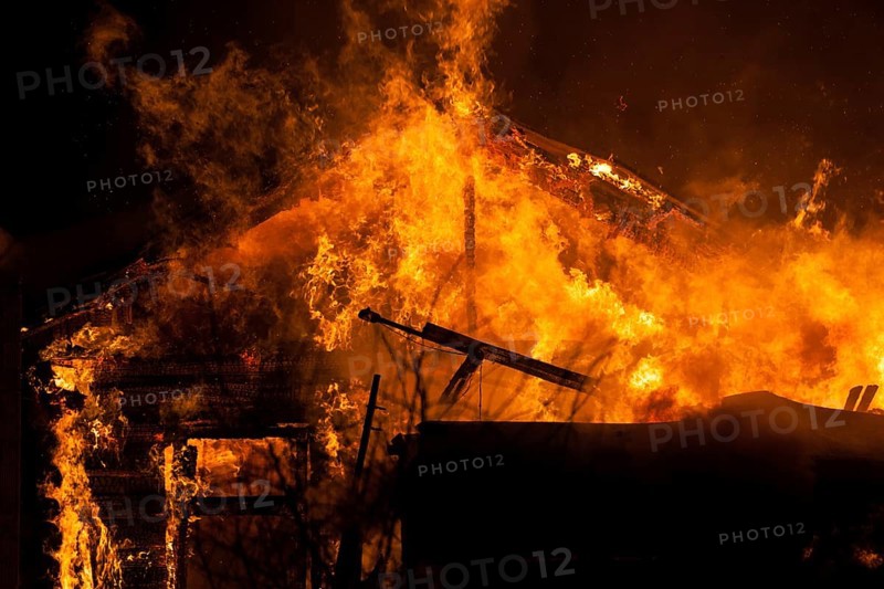 Arson or nature disaster, burning fire flame on wooden house roof