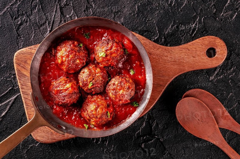 Meatballs. Beef meat balls, overhead flat lay shot in a pan, with parsley and tomato sauce, on a black background, with wooden spoons, Food photography