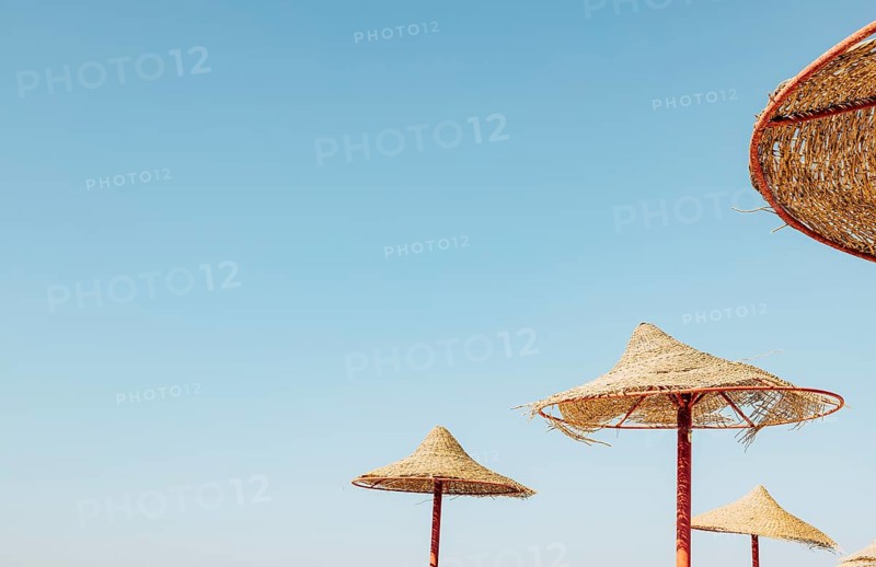 Looking up at wooden straw umbrella or thatched hut from below against beautiful cloudy blue sky view on tropical Egypt beach. Summer or winter holiday concept. Egyptian resort.
