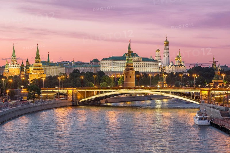 Illuminated Moscow Kremlin and Moscow River with bridge in the summer evening. Pink sky. Russia