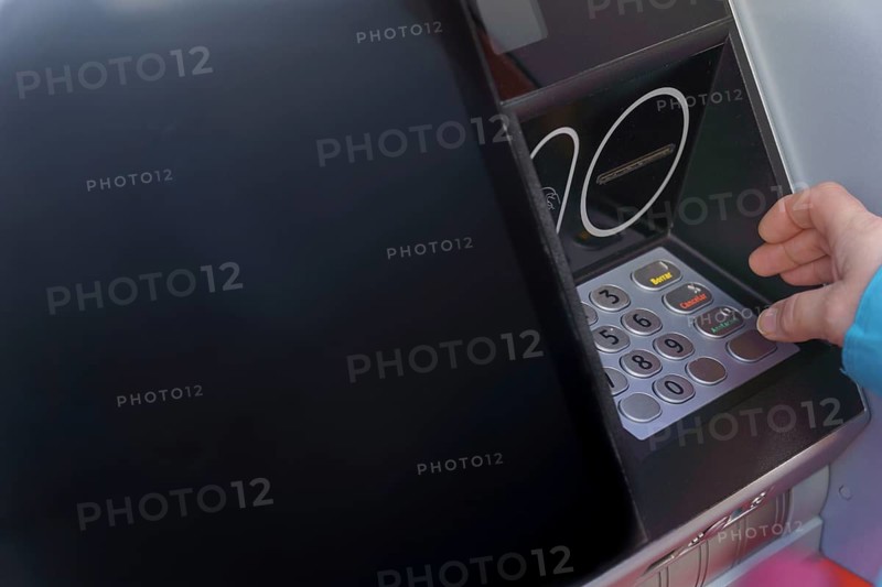 Woman typing her PIN number into an ATM machine to withdraw cash