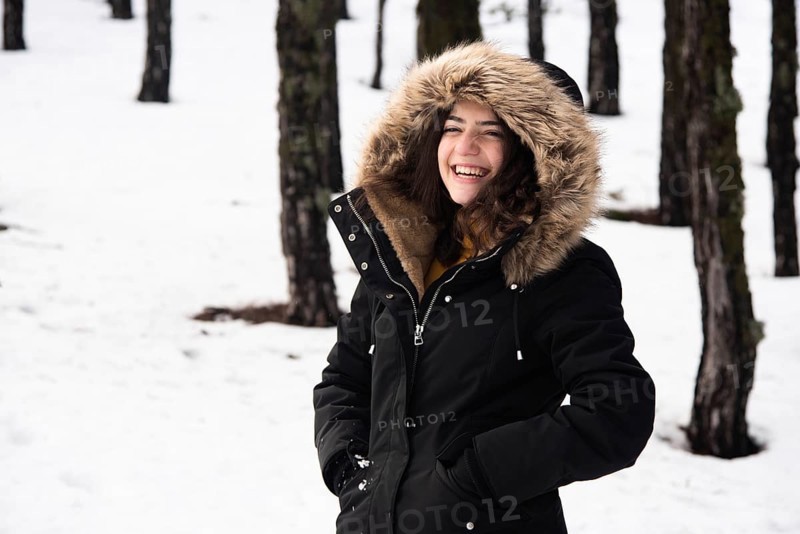 Young happy and beautiful teenage girl dressed in winter clothing standing at snow and smiling. Troodos mountains in Cyprus
