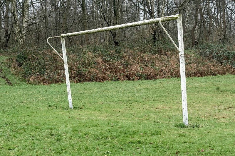 Poorly maintained soccer pitch with old soccer goal in the rain