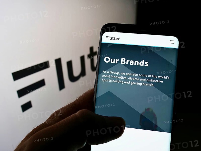 Stuttgart, Germany, 01-06-2022: Person holding smartphone with webpage of Irish bookmaking company Flutter Entertainment plc on screen with logo. Focus on center of phone display, Europe
