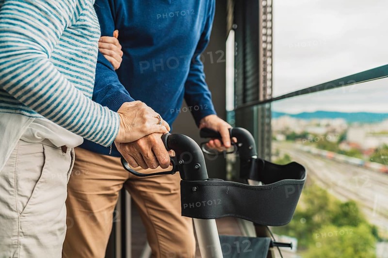 Close up unrecognizable senior couple holding hands while standing outside on the balcony